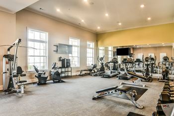 A spacious fitness room with cardio equipment and a flat screen tv